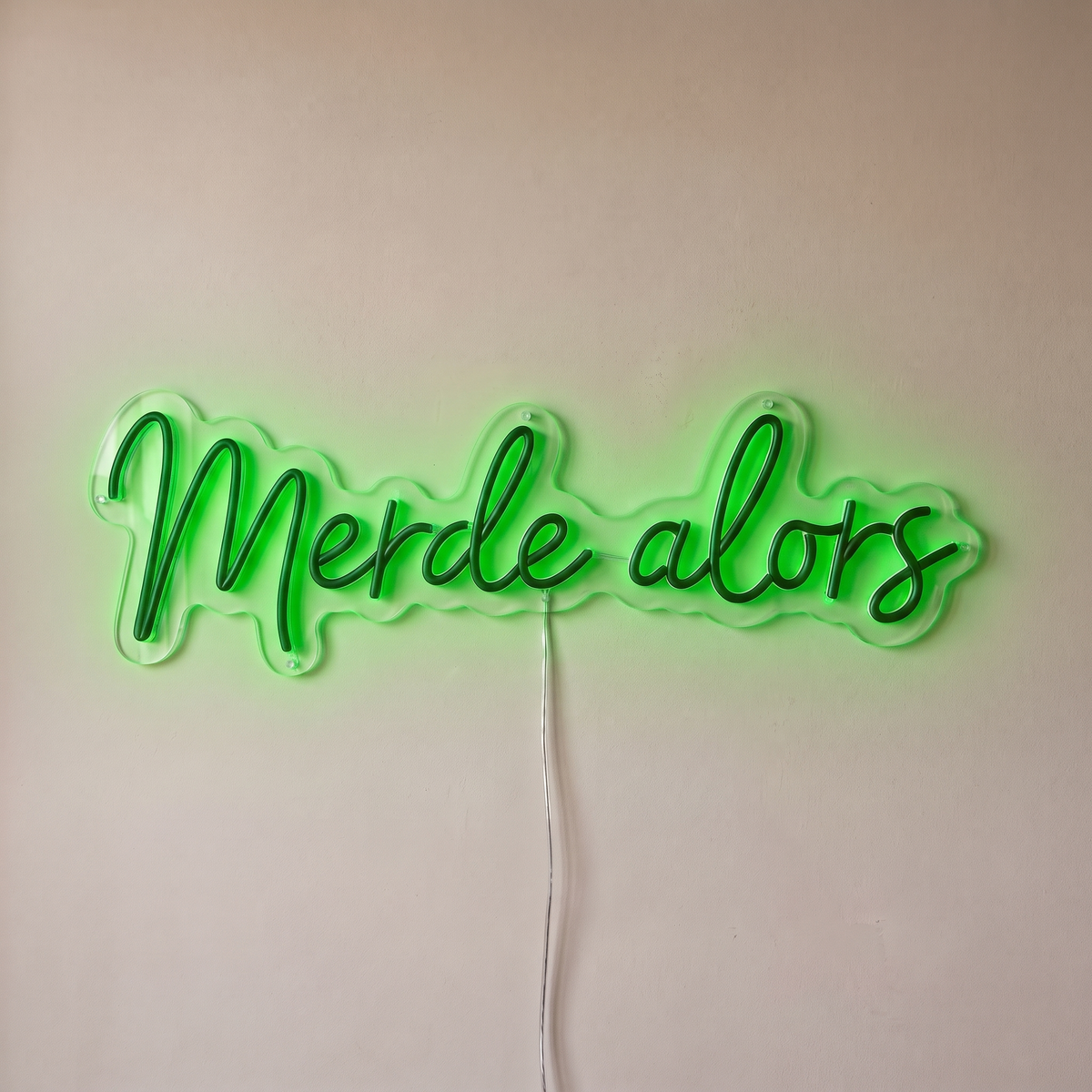 Néon mural « Merde alors » vert, gros plan sur fond beige