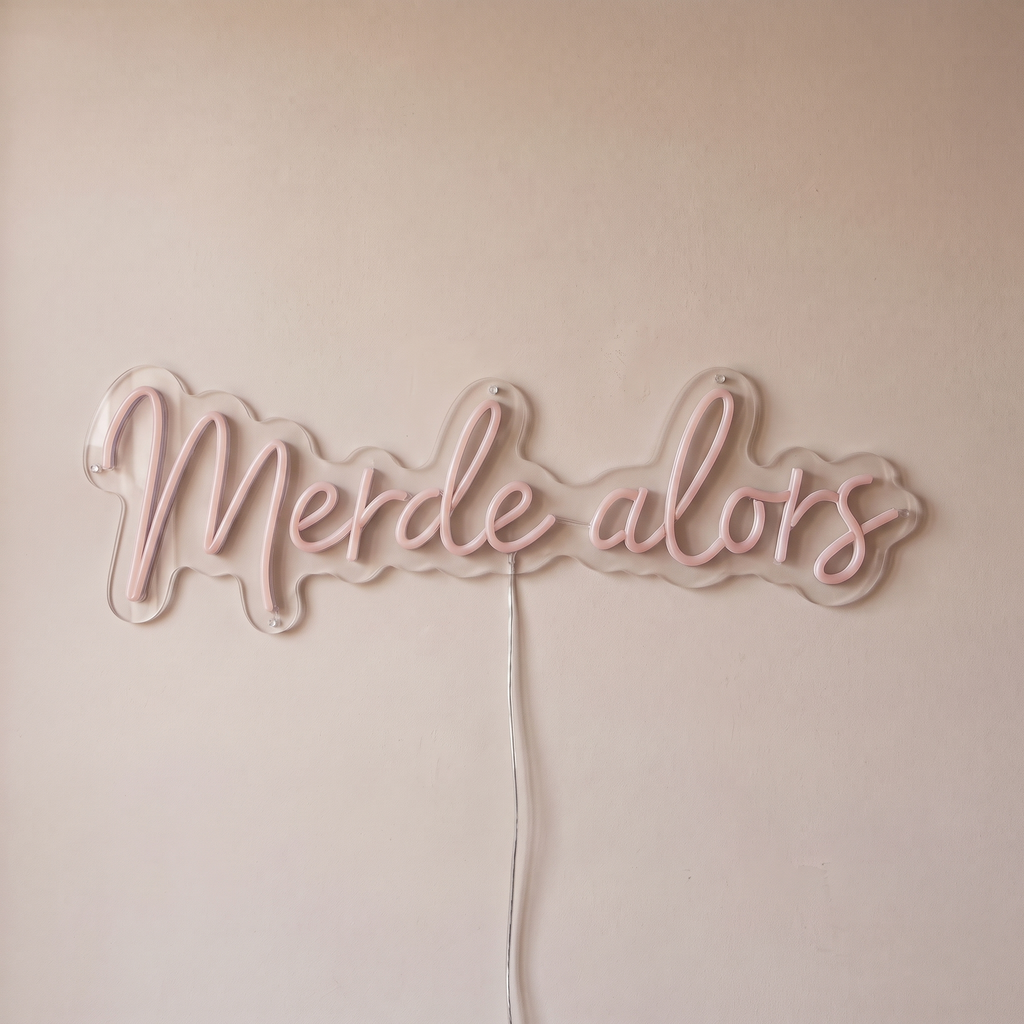 Néon mural « Merde alors » rose pâle, gros plan sur fond beige