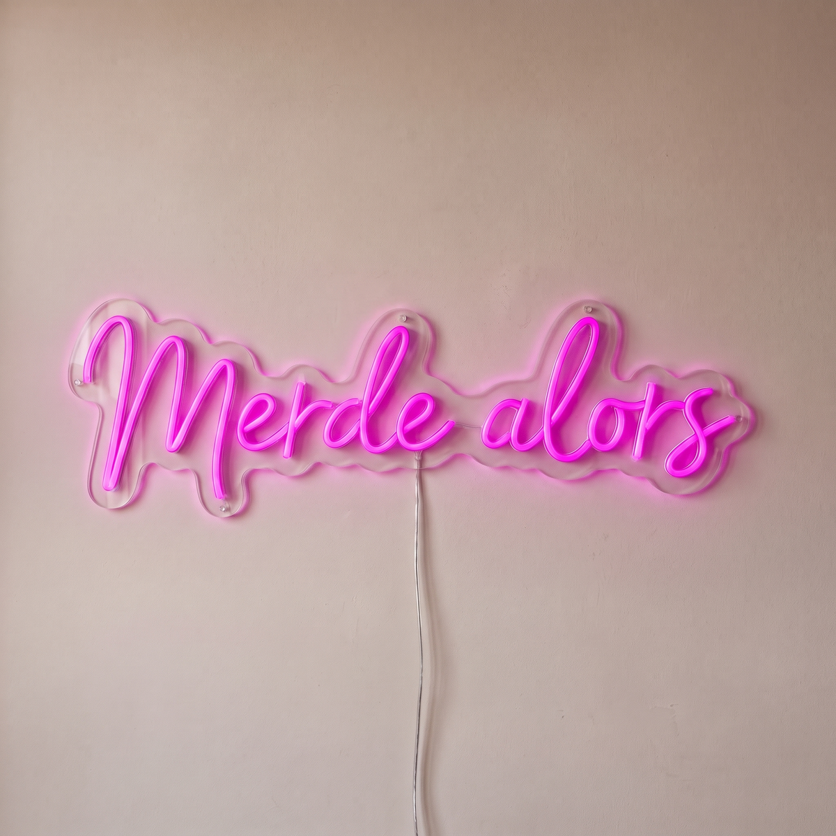 Néon mural « Merde alors » rose, gros plan sur fond beige
