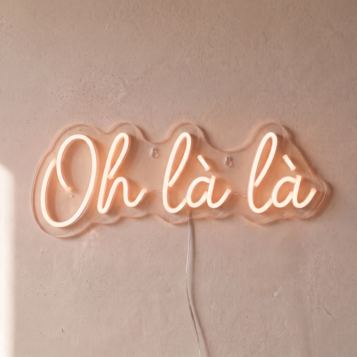 Néon mural « Oh là là » blanc chaud, gros plan sur fond beige