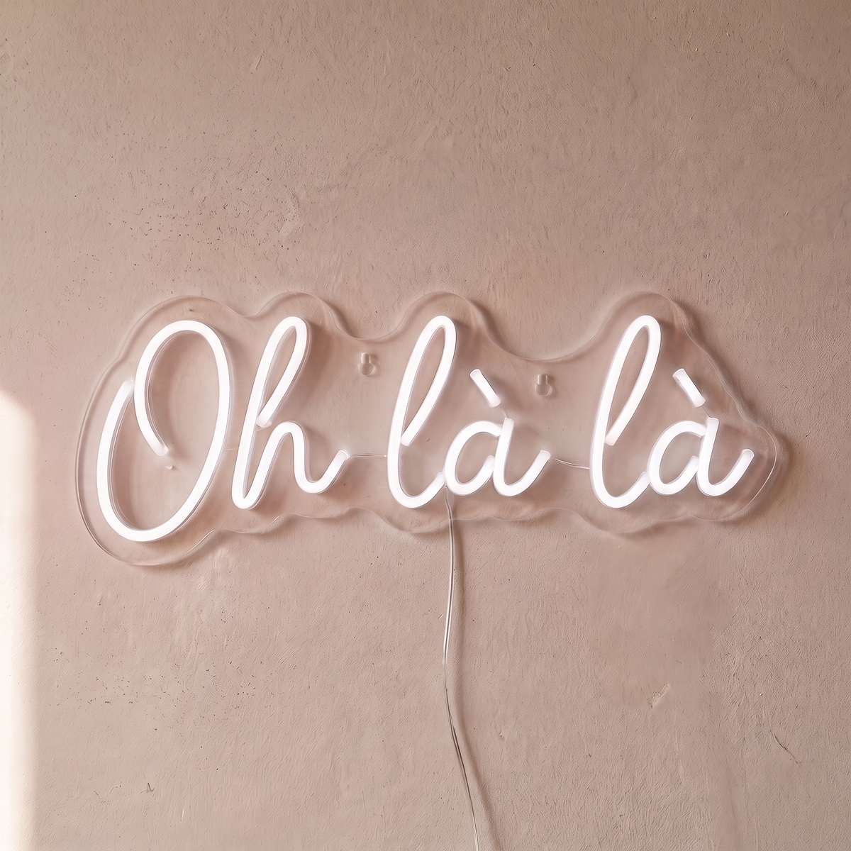 Néon mural « Oh là là » blanc, gros plan sur fond beige