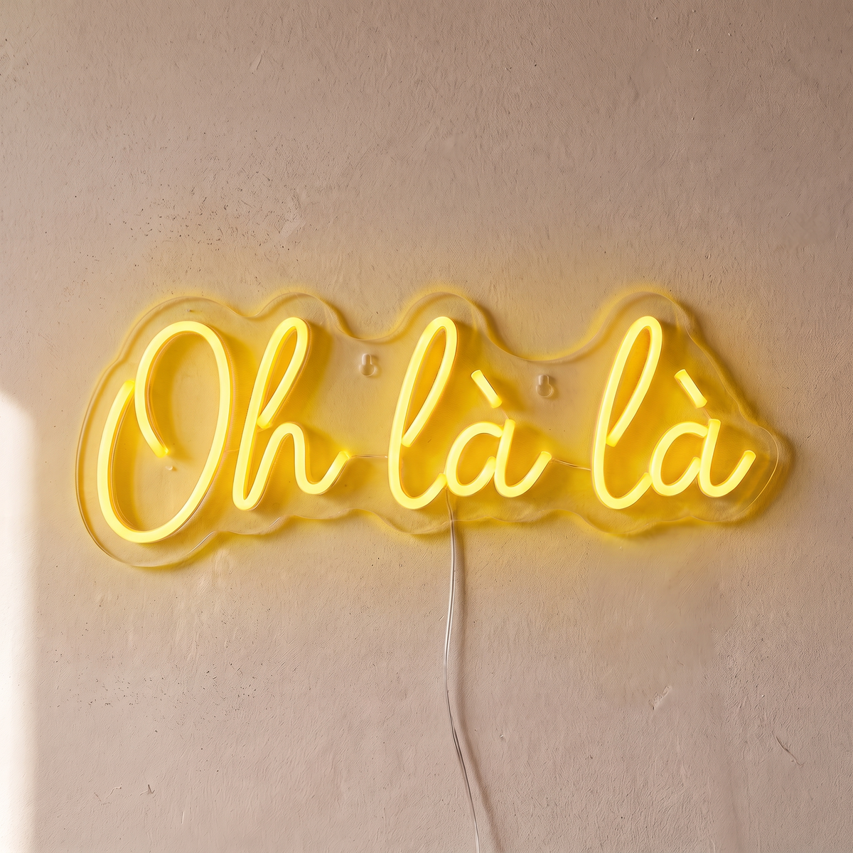 Néon mural « Oh là là » jaune, gros plan sur fond beige