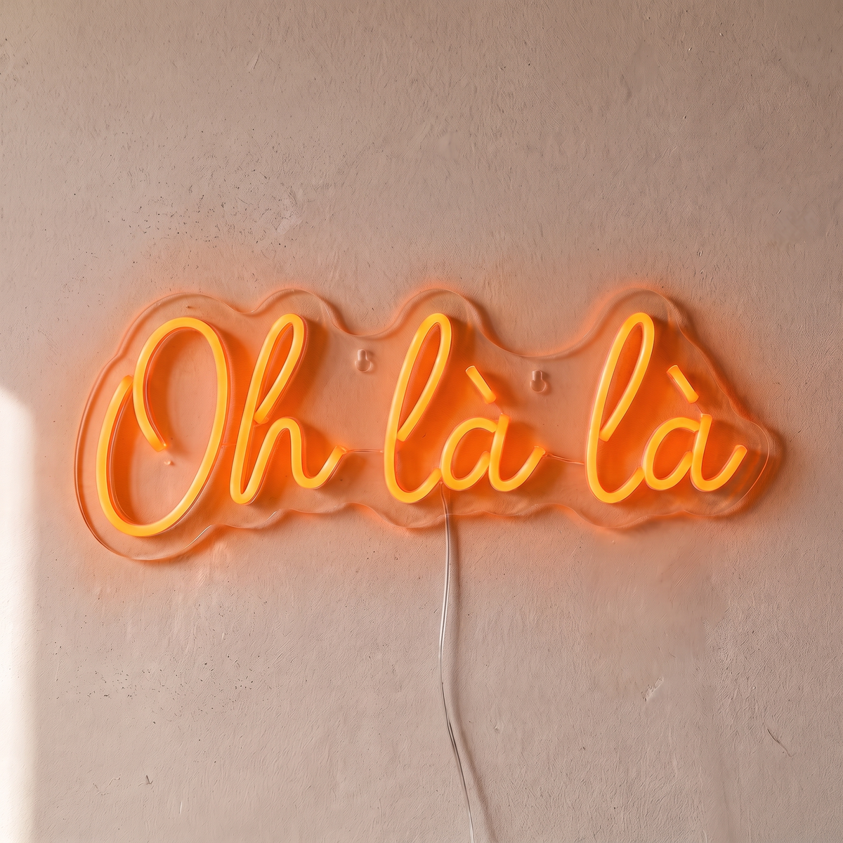 Néon mural « Oh là là » orange, gros plan sur fond beige