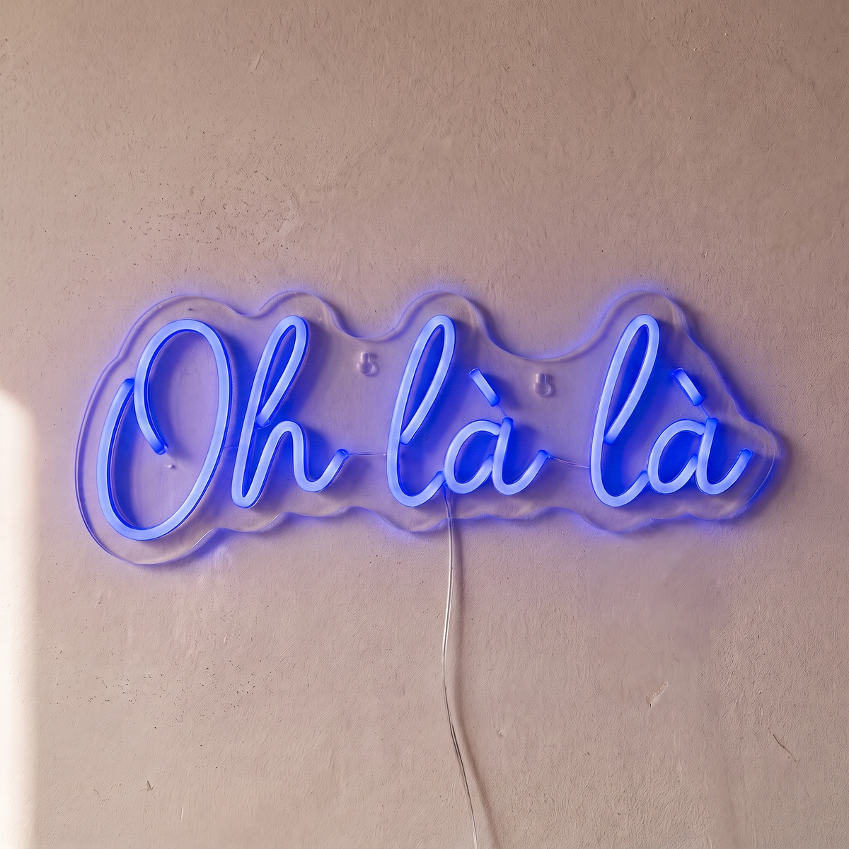 Néon mural « Oh là là » bleu, gros plan sur fond beige