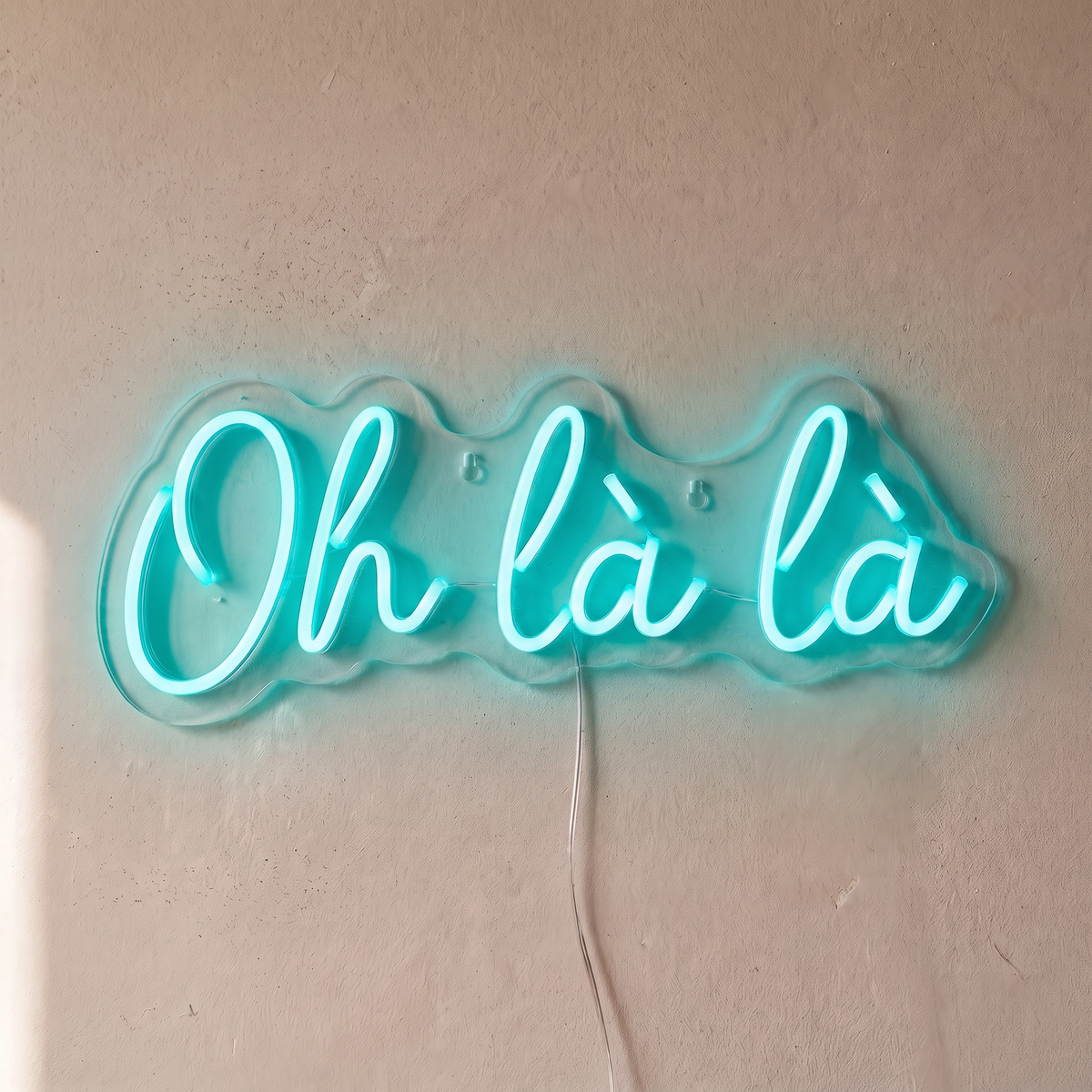 Néon mural « Oh là là » turquoise, gros plan sur fond beige
