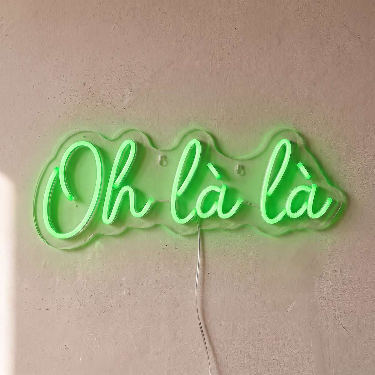Néon mural « Oh là là » vert, gros plan sur fond beige