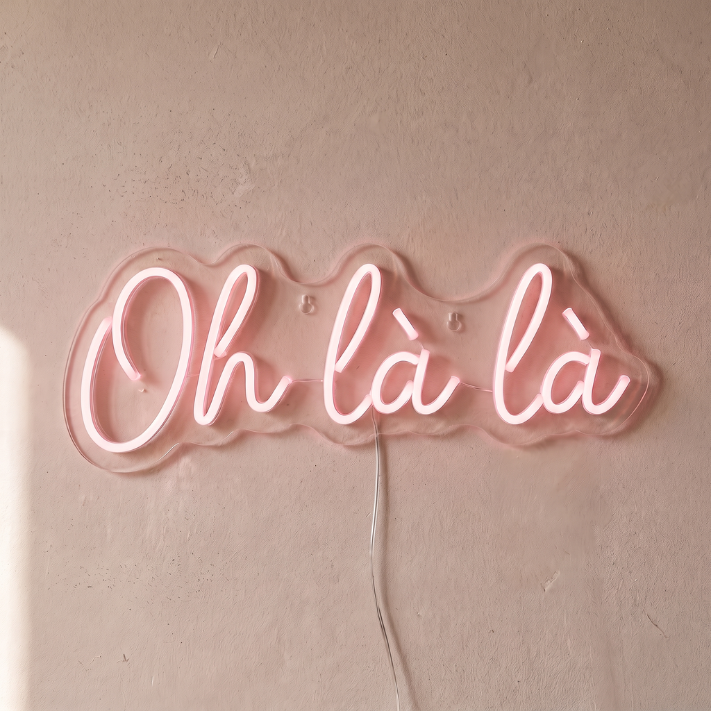 Néon mural « Oh là là » rose pâle, gros plan sur fond beige