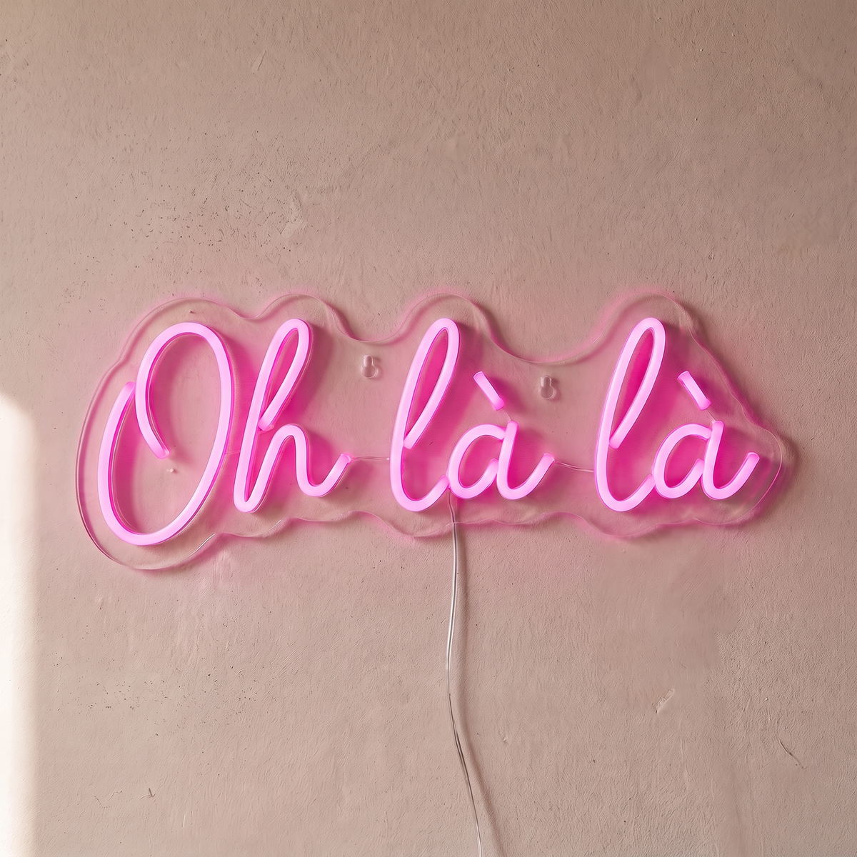 Néon mural « Oh là là » rose, gros plan sur fond beige