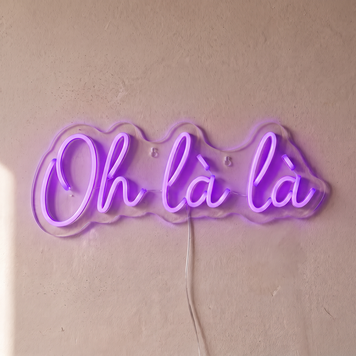 Néon mural « Oh là là » violet, gros plan sur fond beige