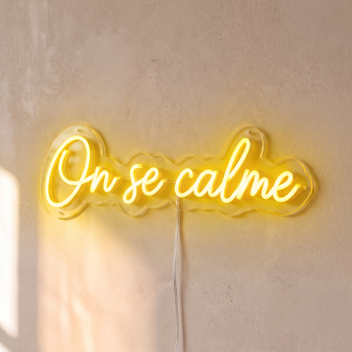 Néon mural « On se calme » jaune, gros plan sur fond beige