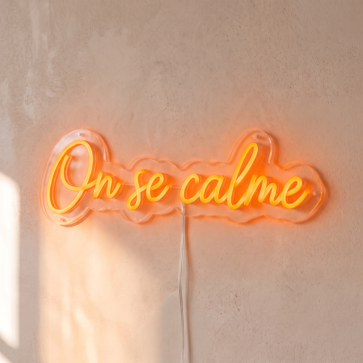 Néon mural « On se calme » orange, gros plan sur fond beige