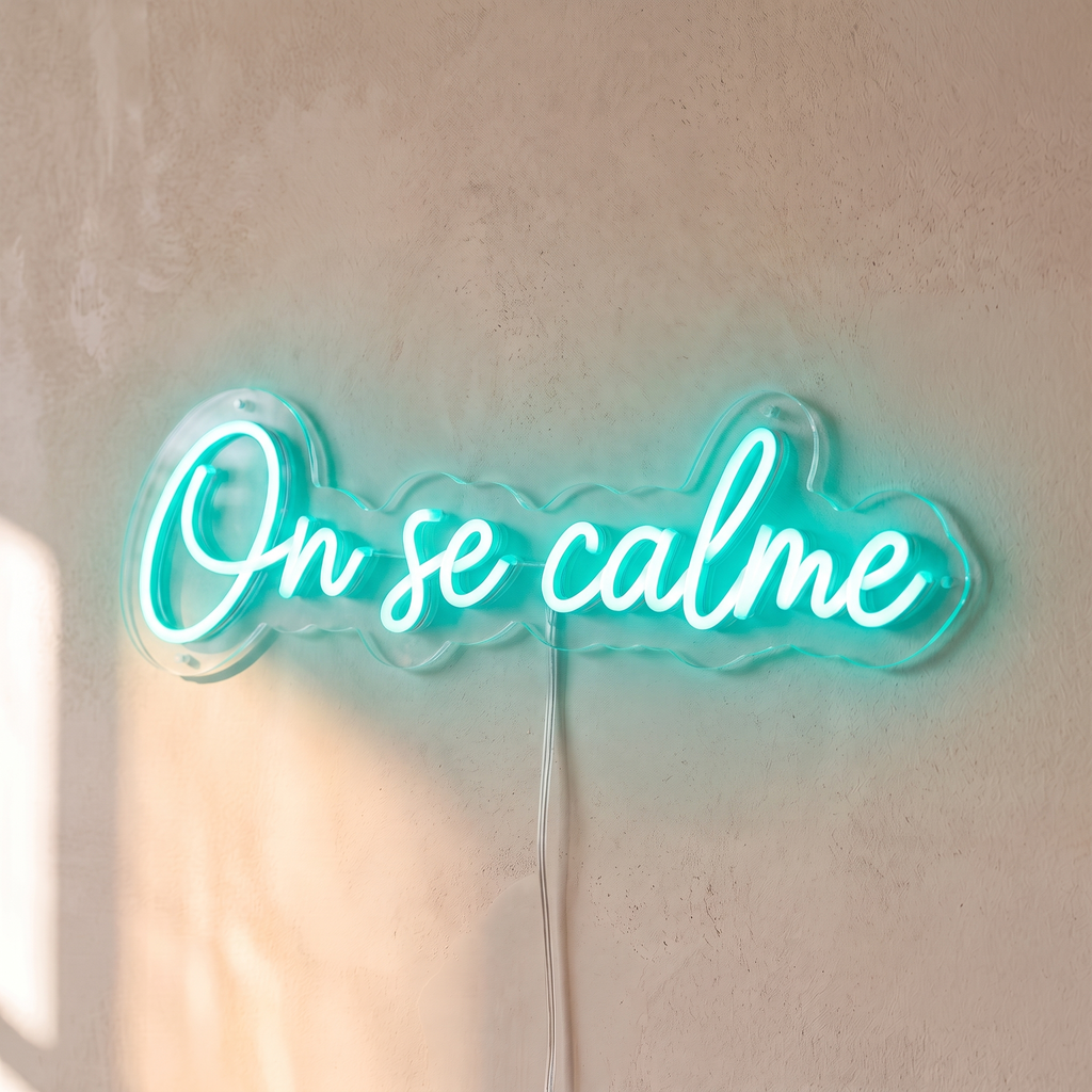 Néon mural « On se calme » turquoise, gros plan sur fond beige