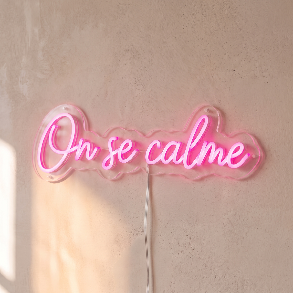 Néon mural « On se calme » rose, gros plan sur fond beige