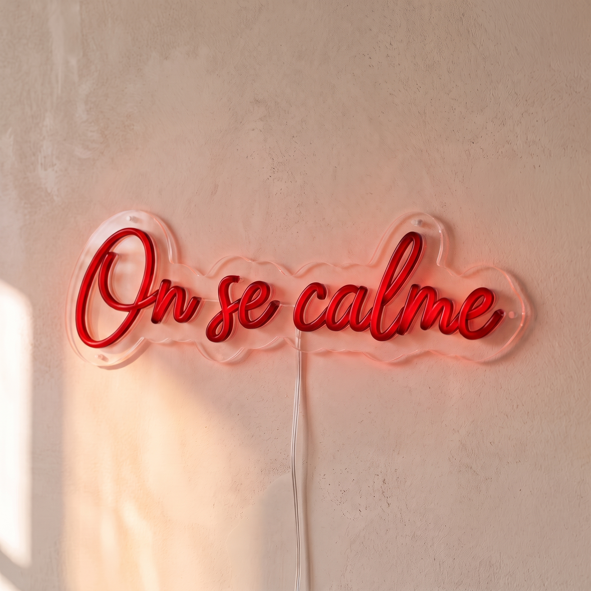 Néon mural « On se calme » rouge, gros plan sur fond beige
