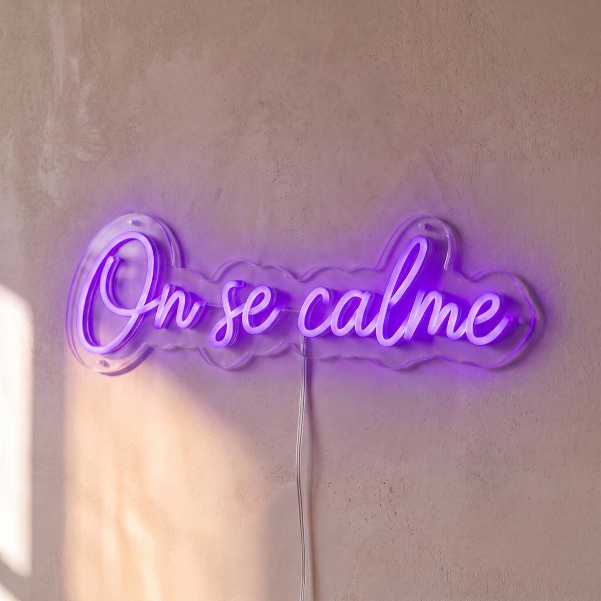 Néon mural « On se calme » violet, gros plan sur fond beige