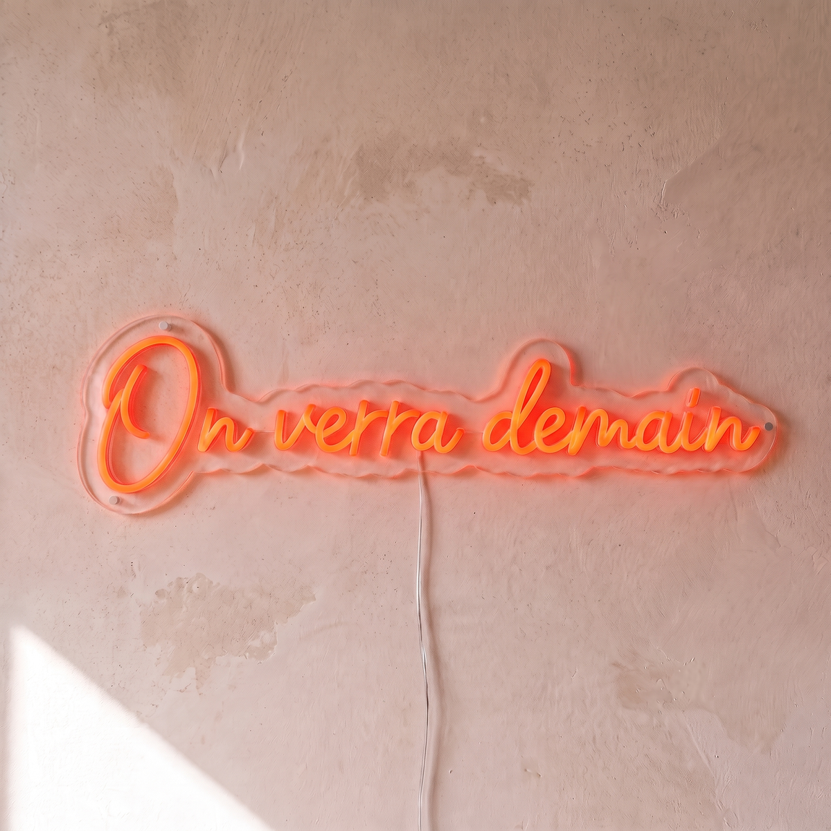 Néon mural « On verra demain » rouge orangé, gros plan sur fond beige