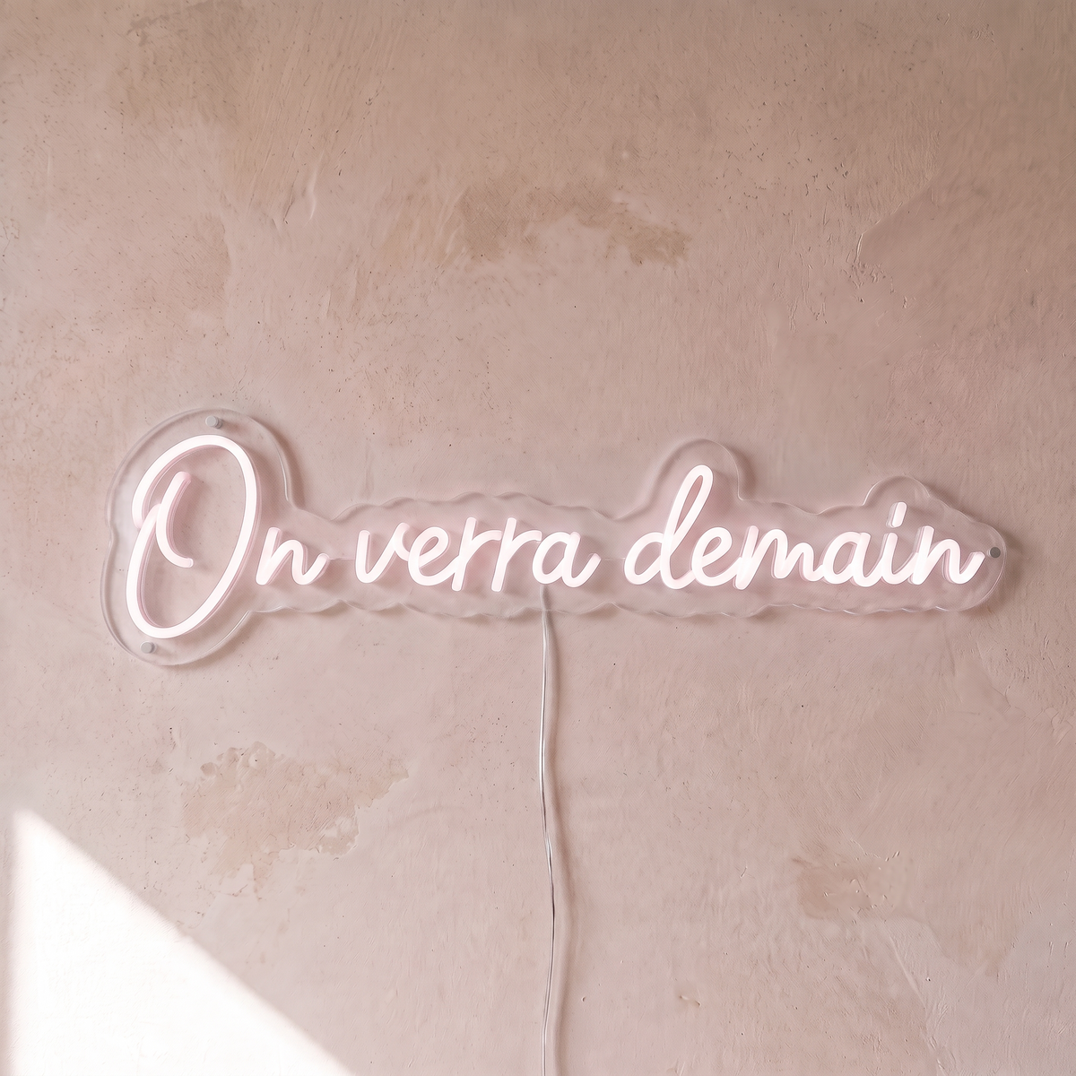 Néon mural « On verra demain » rose pâle, gros plan sur fond beige