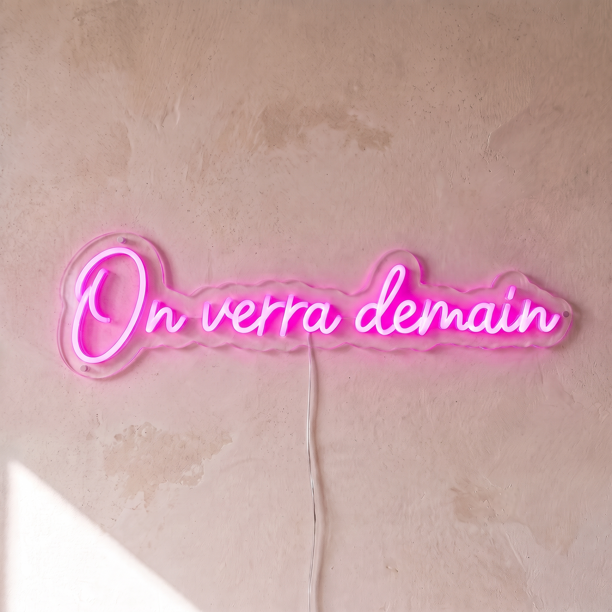 Néon mural « On verra demain » rose, gros plan sur fond beige