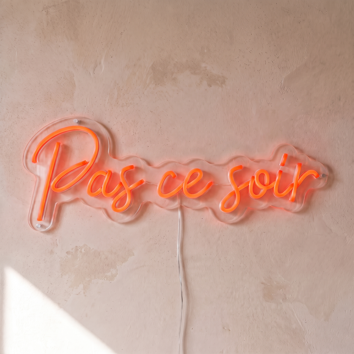 Néon mural « Pas ce soir » rouge orangé, gros plan sur fond beige