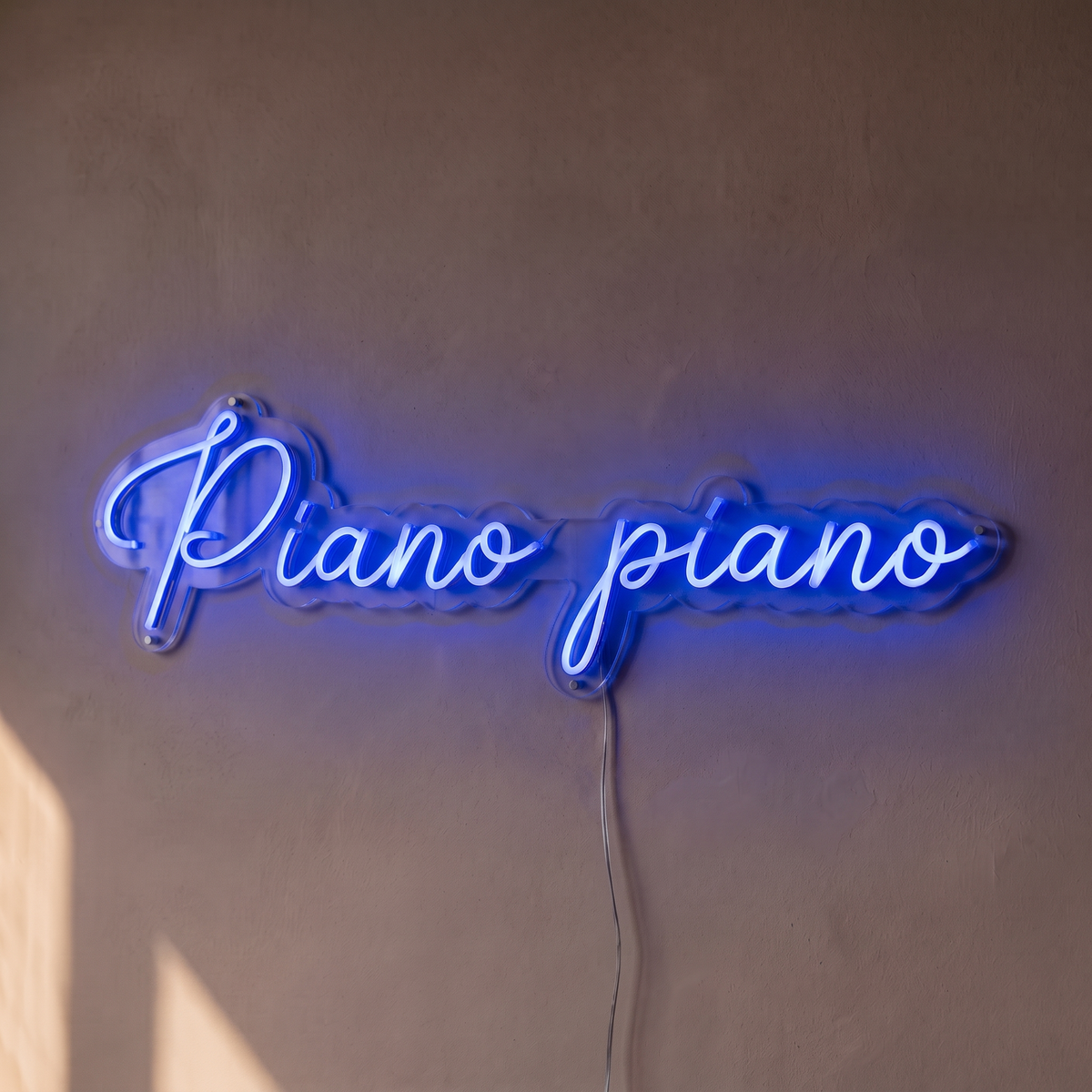 Néon mural « Piano piano » bleu, gros plan sur fond beige