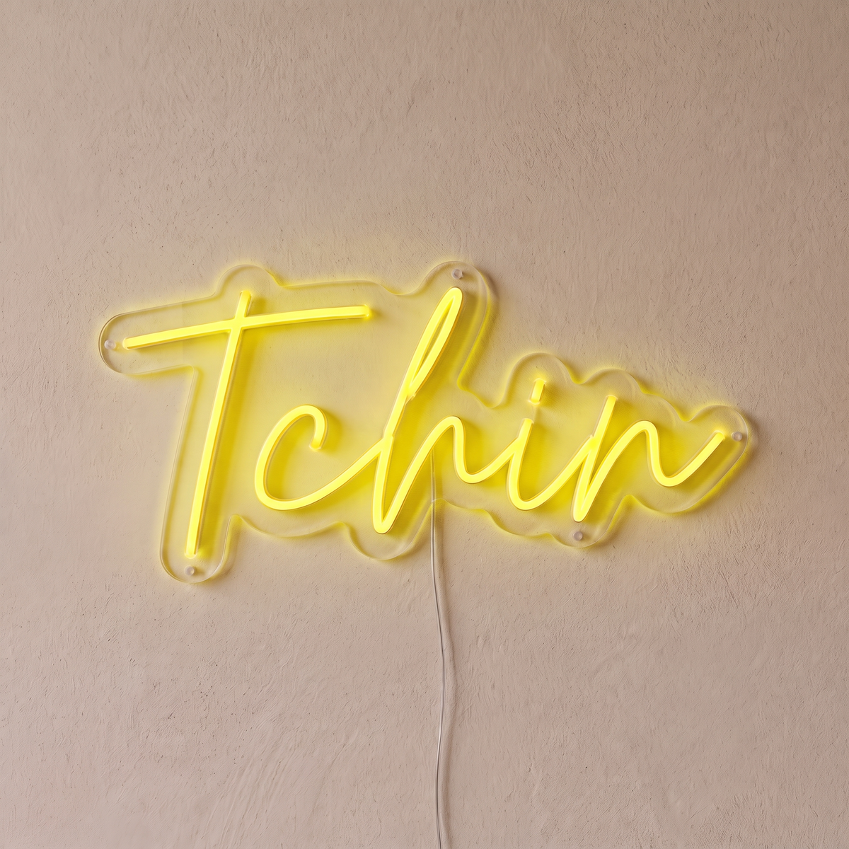 Néon mural « Tchin » jaune, gros plan sur fond beige