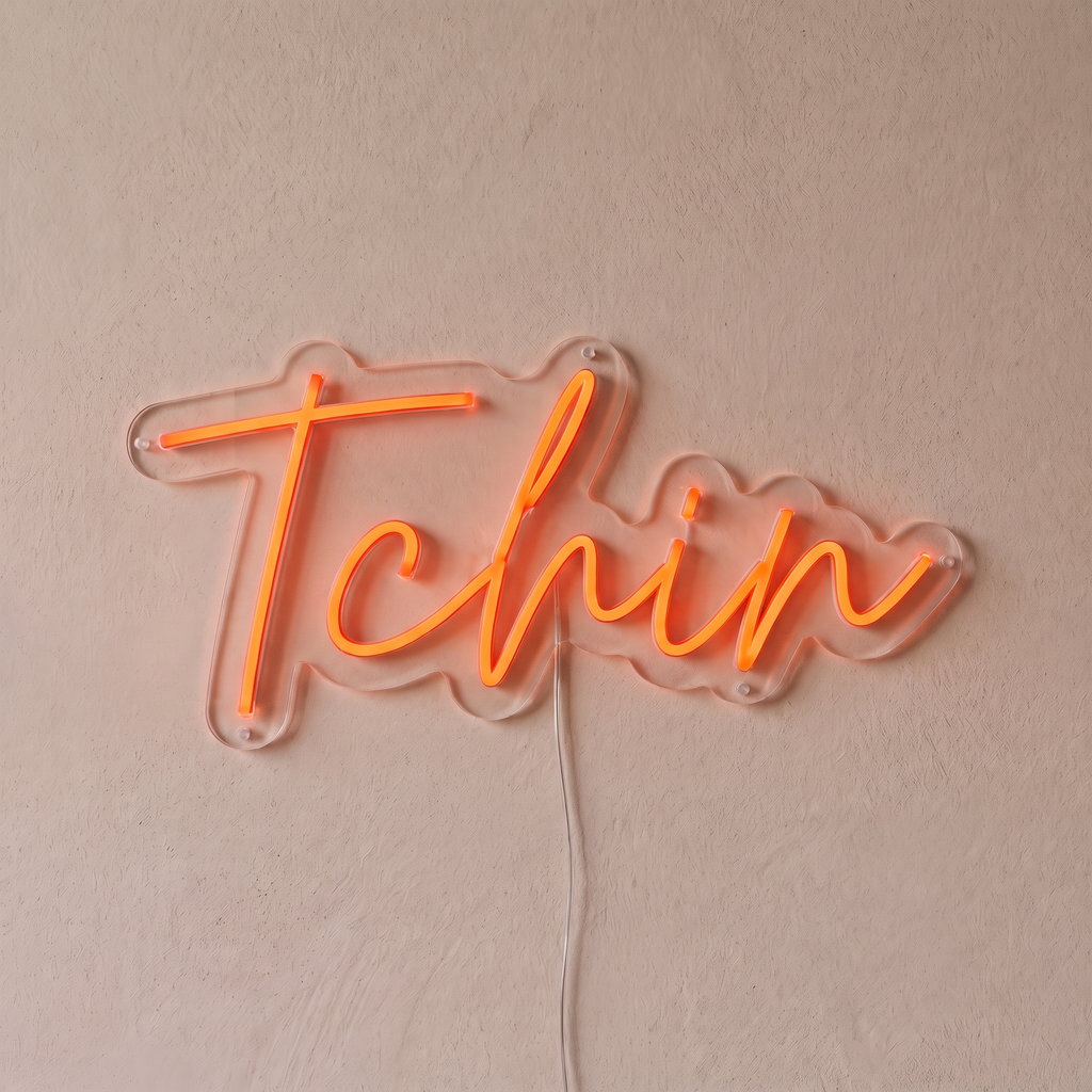 Néon mural « Tchin » rouge orangé, gros plan sur fond beige