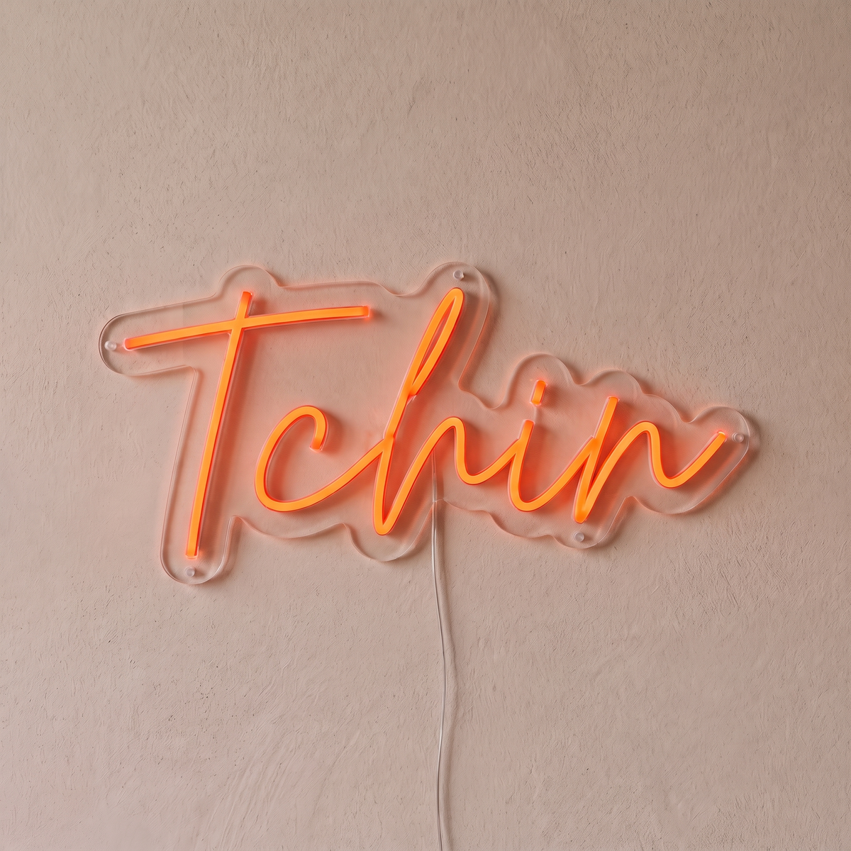 Néon mural « Tchin » rouge orangé, gros plan sur fond beige