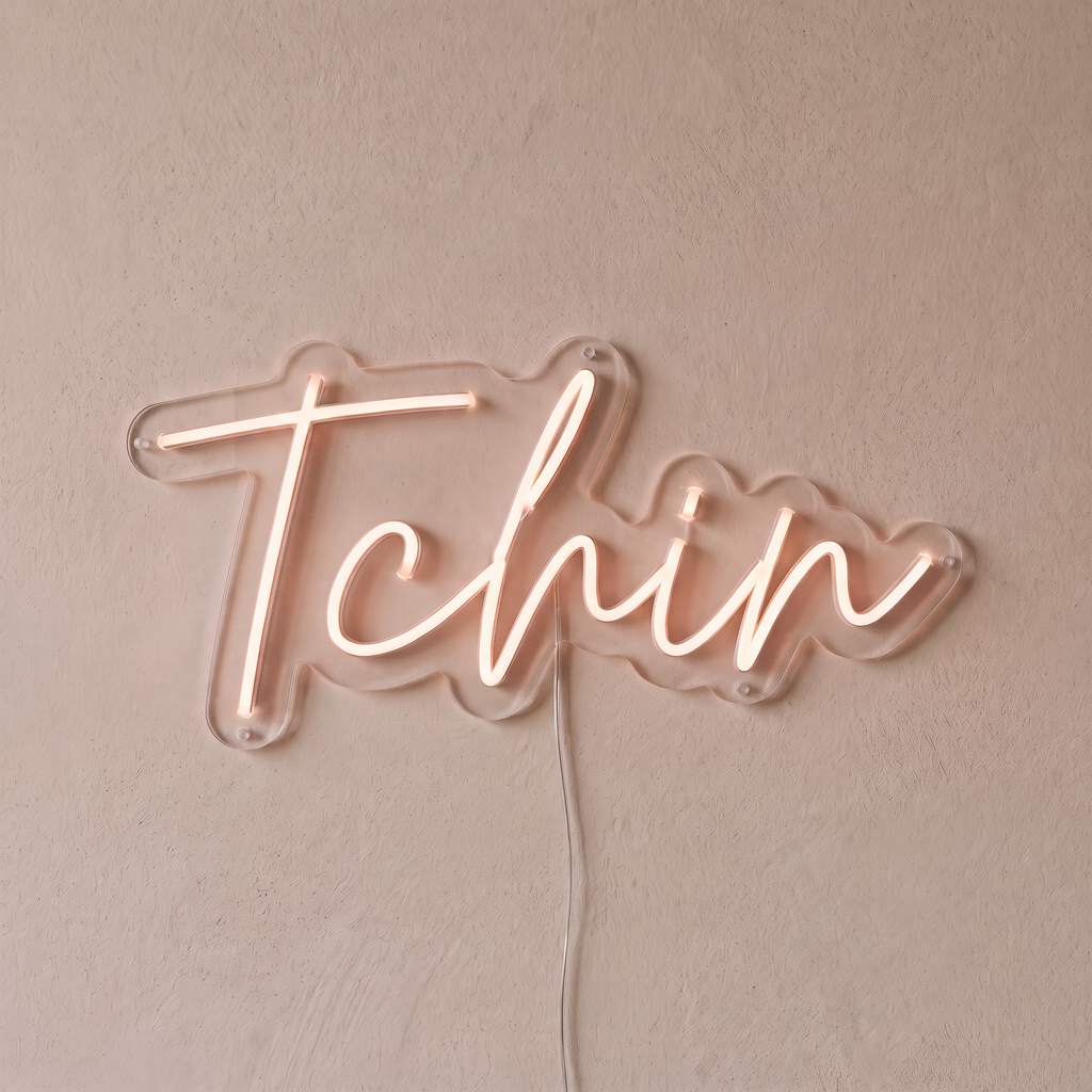 Néon mural « Tchin » rose pâle, gros plan sur fond beige