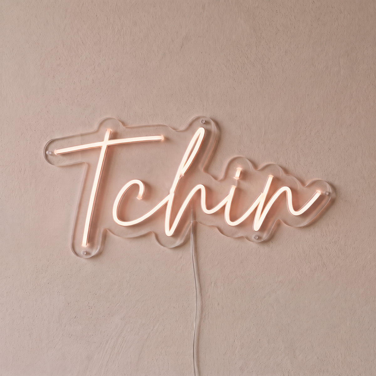 Néon mural « Tchin » rose pâle, gros plan sur fond beige