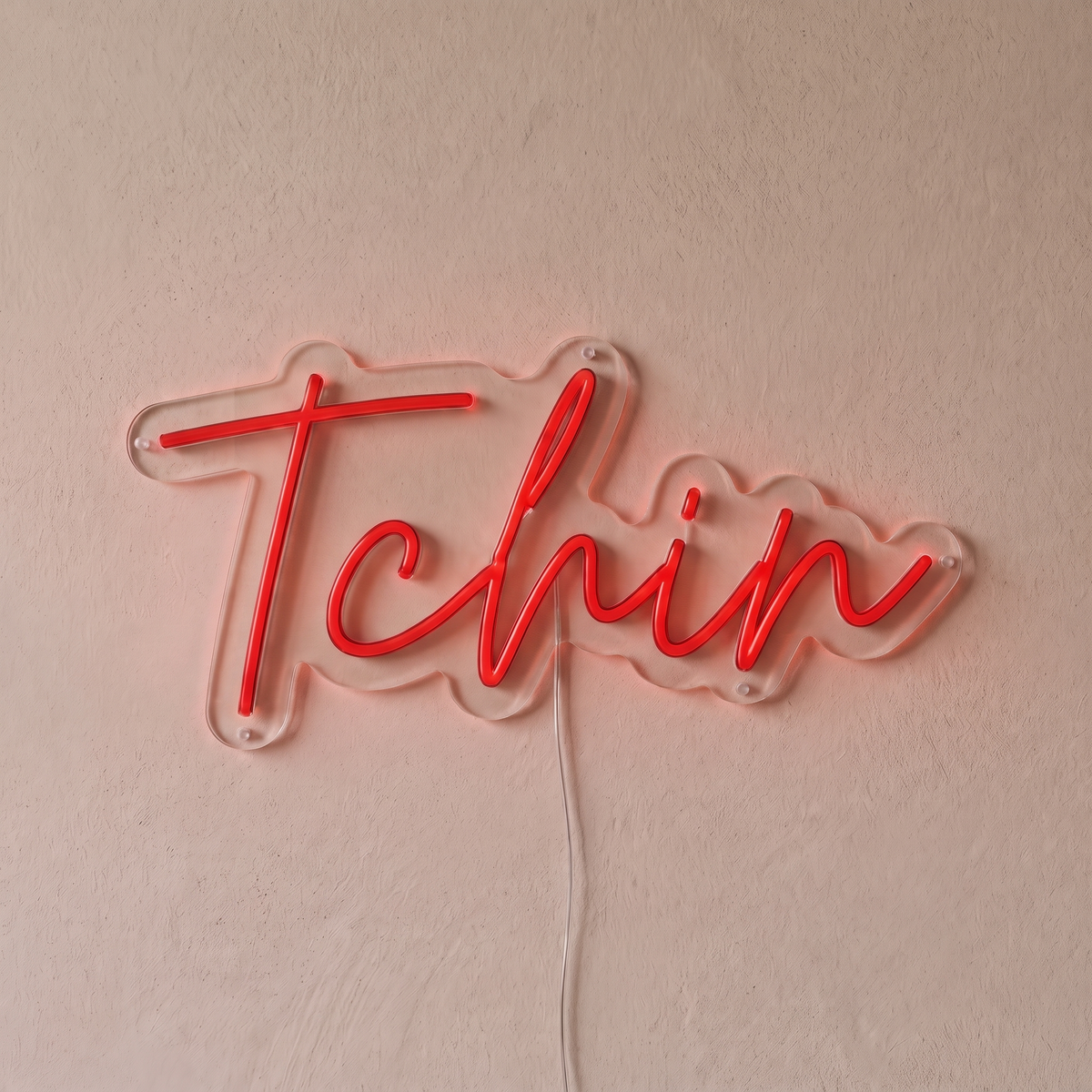 Néon mural « Tchin » rouge, gros plan sur fond beige