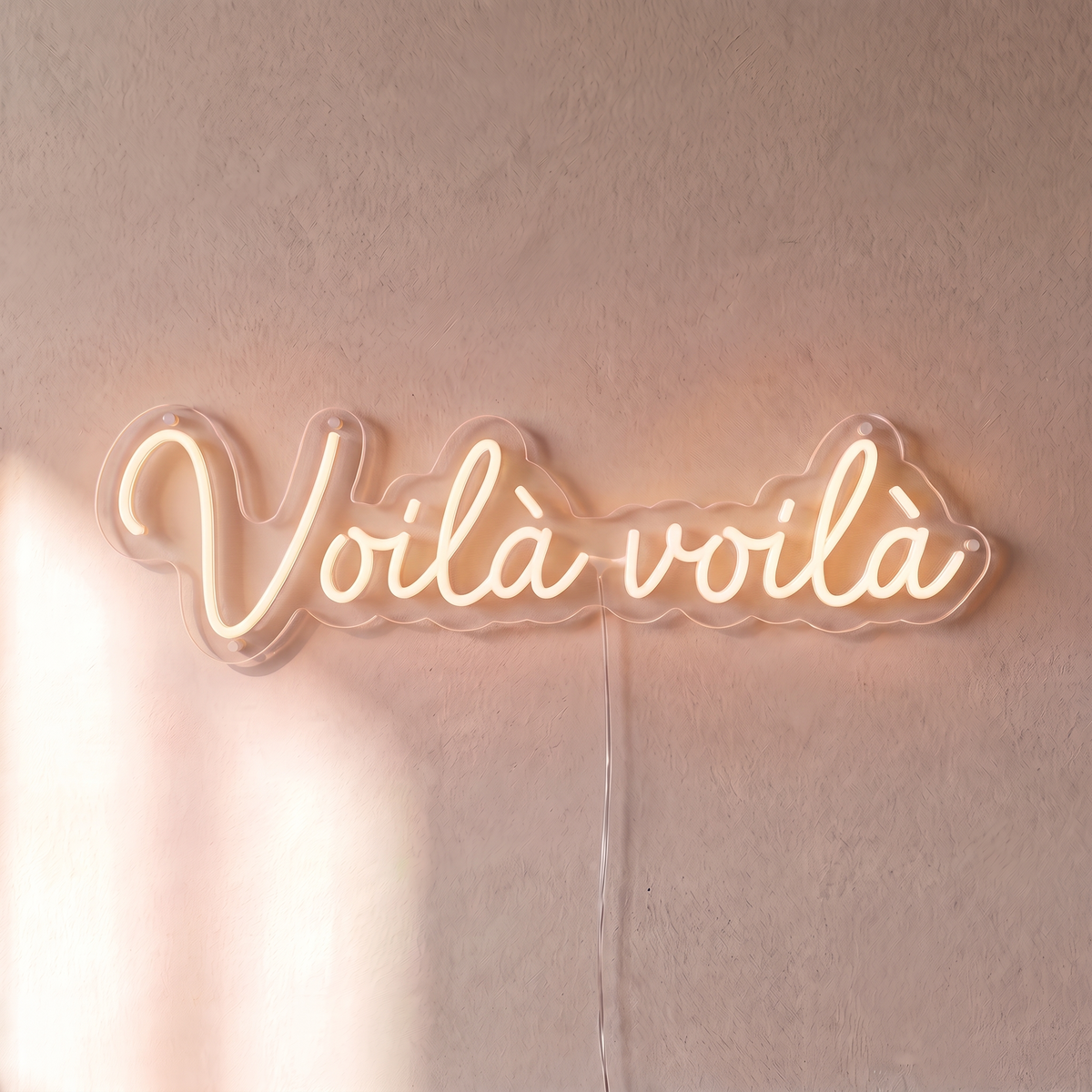 Néon mural « Voilà voilà » blanc chaud, gros plan sur fond beige