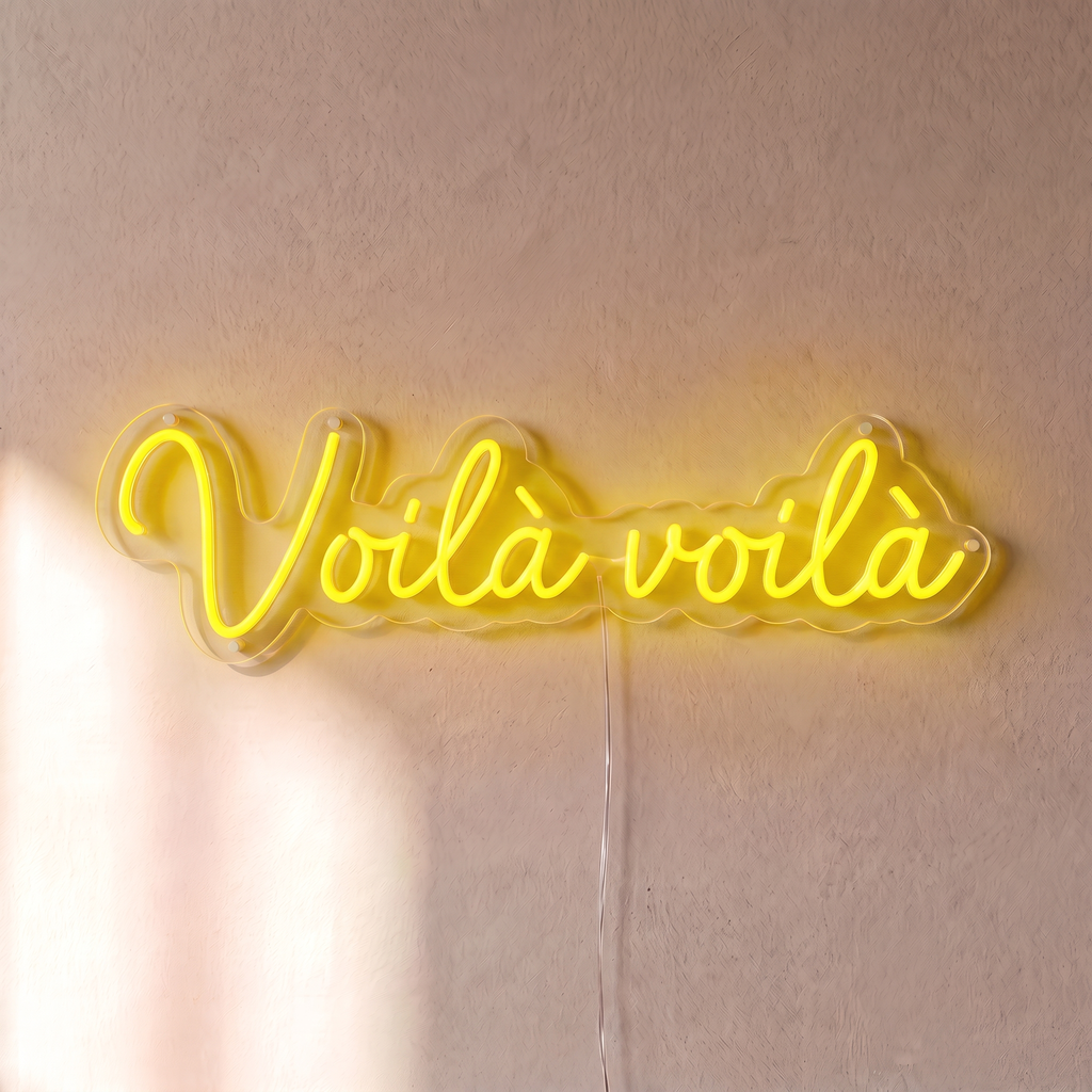 Néon mural « Voilà voilà » jaune, gros plan sur fond beige