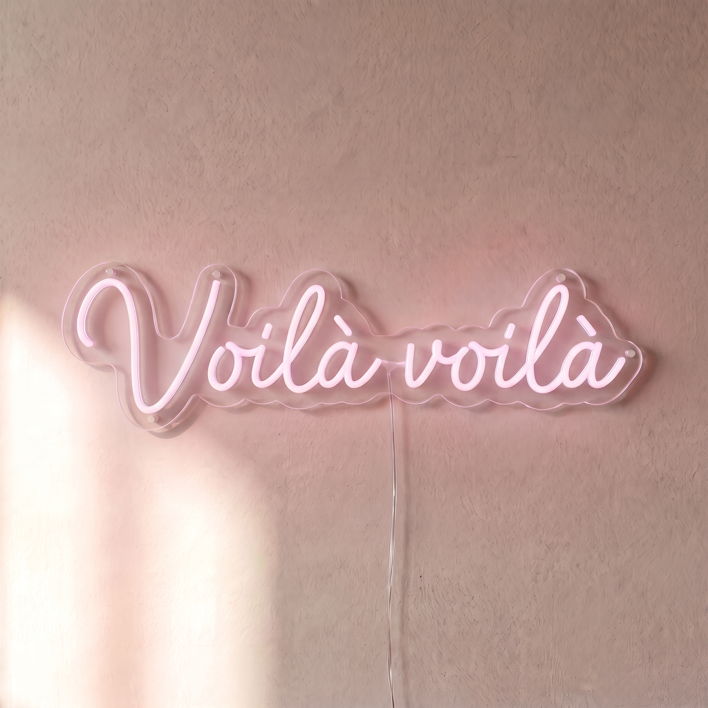 Néon mural « Voilà voilà » rose pâle, gros plan sur fond beige