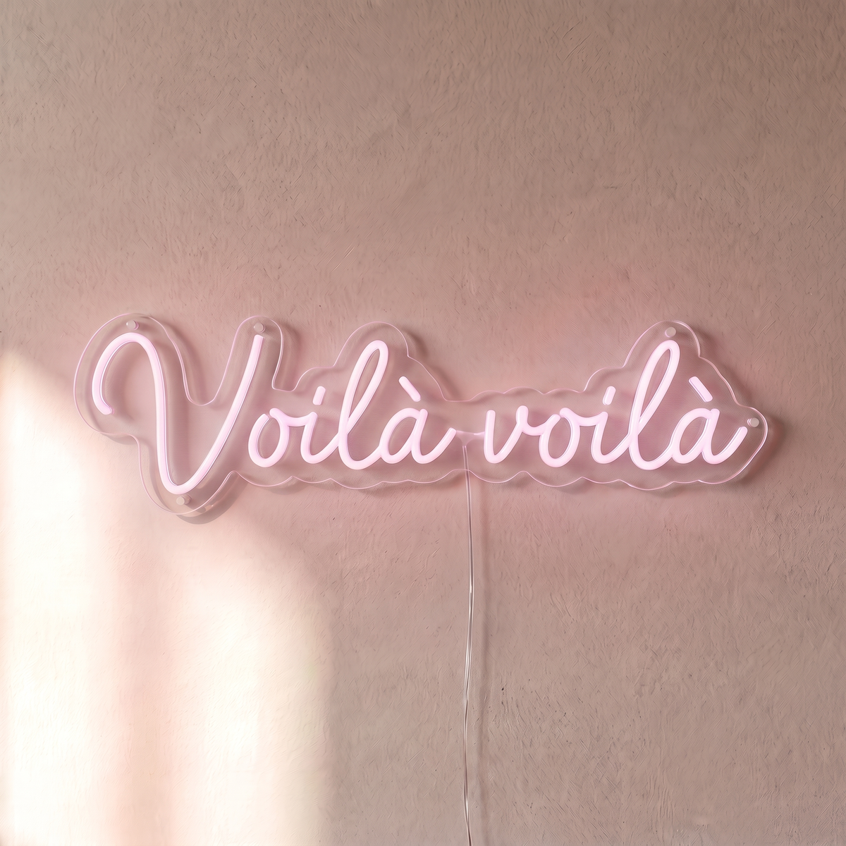 Néon mural « Voilà voilà » rose pâle, gros plan sur fond beige