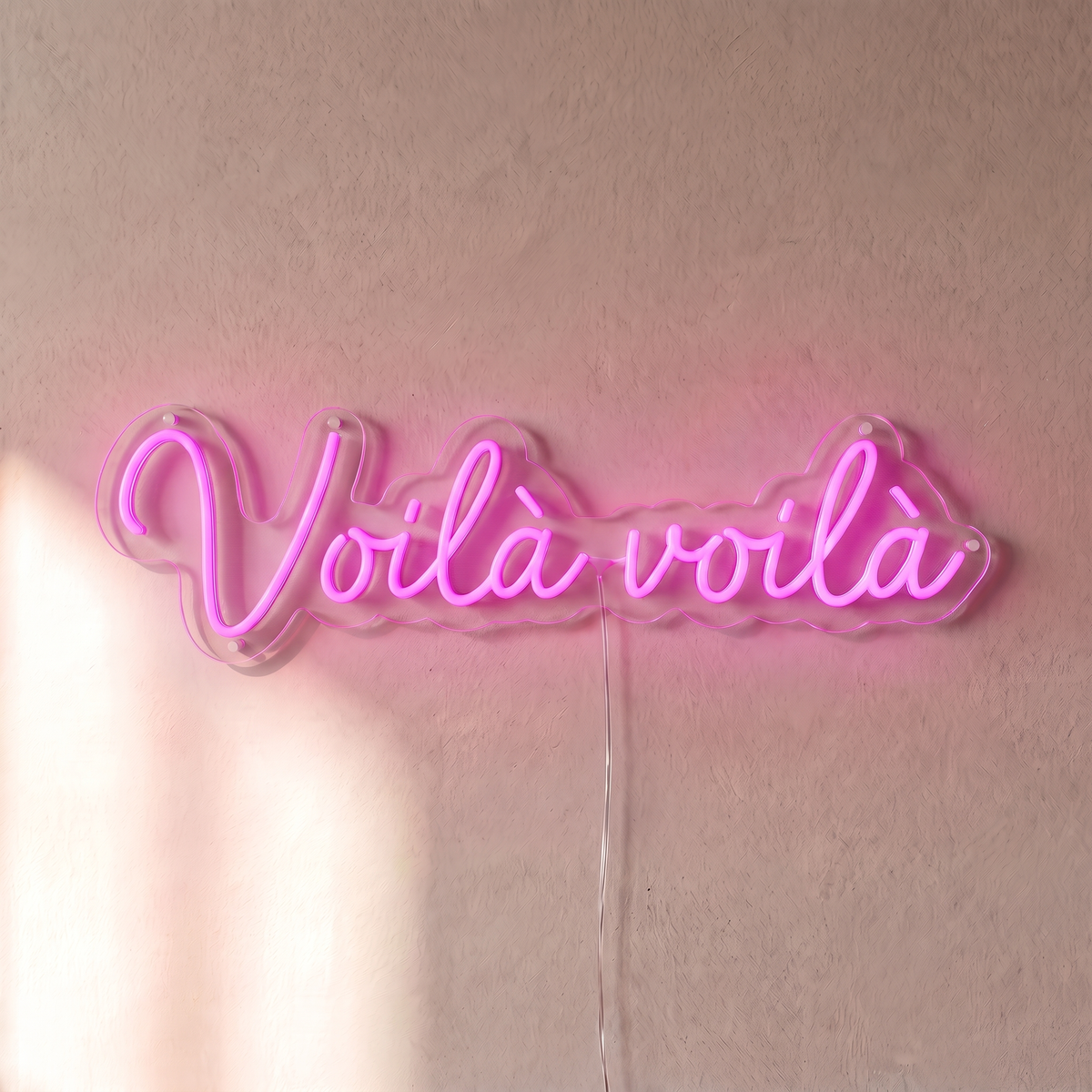 Néon mural « Voilà voilà » rose, gros plan sur fond beige